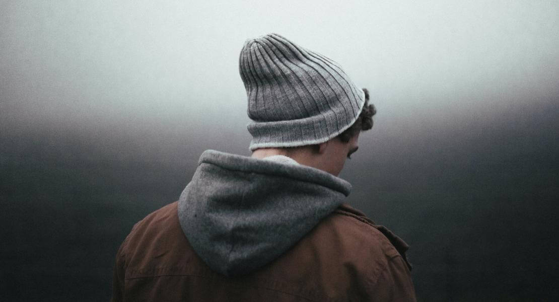 Personne d'apparence masculine de dos, regardant le sol