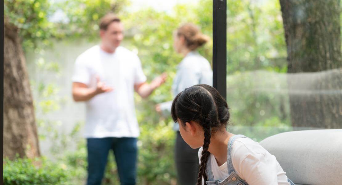 Enfant qui observe ses parents qui se disputent en arrière-plan