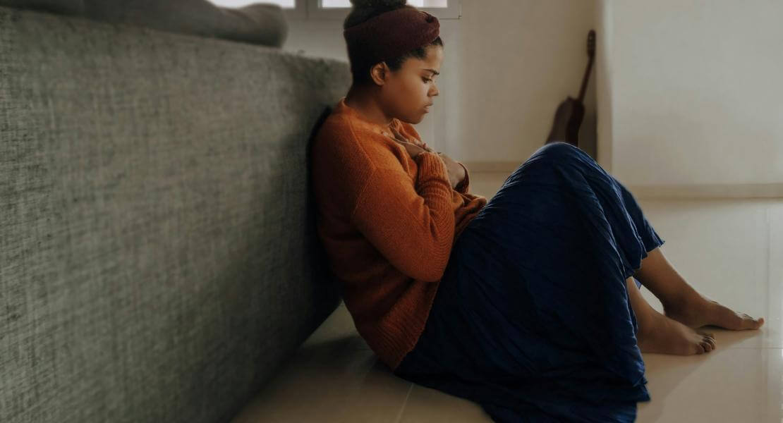 Femme triste assise au pied du sofa