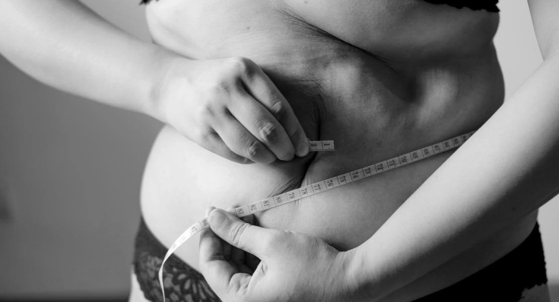 Une femme se mesure le ventre avec un ruban à mesurer